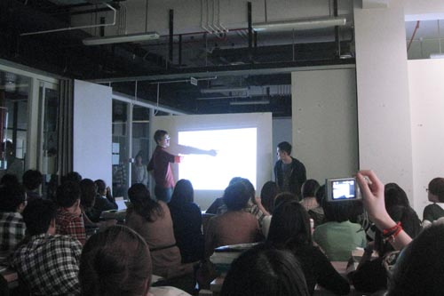Two teachers are talking in front of a projected image
